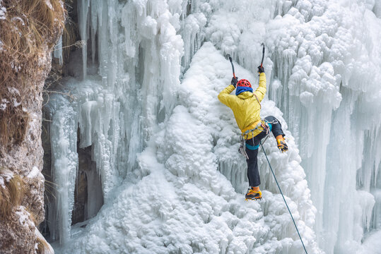 Male alpinist climbing on a frozen waterfall