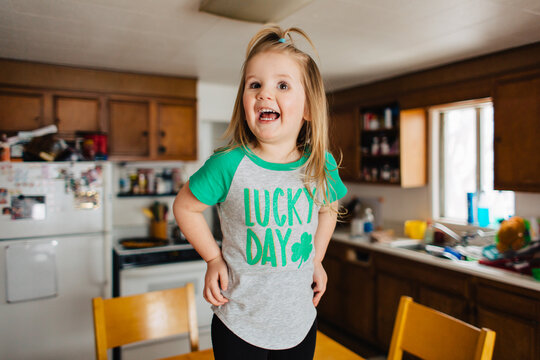 Toddler child in Lucky Day Saint Patrick's Day shirt in kitchen.