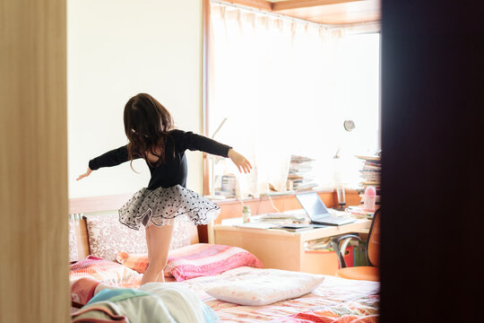 Adorable girl dancing ballet on bed
