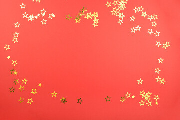 Fototapeta na wymiar christmas composition with decoration on red background with golden confetti stars. Concept holiday atmosphere, new year, celebration, greeting card. Flatlay, top view, frame, copyspace