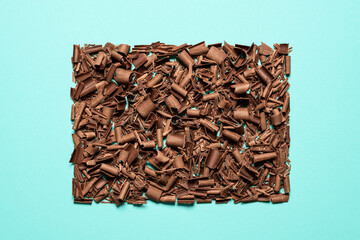Chocolate pieces pile isolated on blue background. Chopped chocolate top view