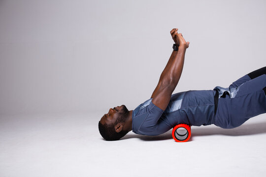 A man is doing exercises on a foam roller on his back. Exercise on a foam roller