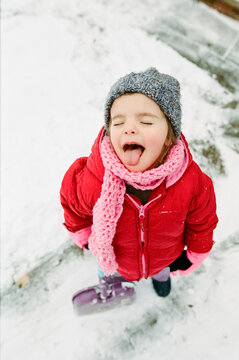 little girl catches snowflakes on tongue