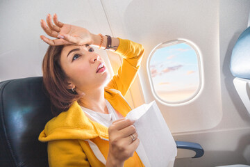 An Asian female traveler suffers from an acute attack of nausea during turbulence on a plane. The woman was seasick and airsock during air flight