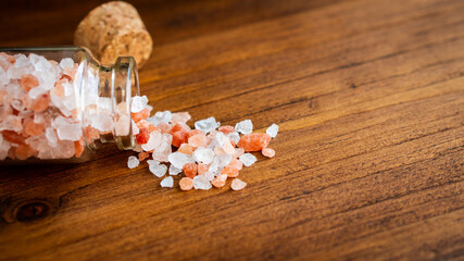 Close up pink and white natural Himalayan crystal rock mountain organic sea salt powder flake cook ingredient in grinder bottle glass on vintage rustic black kitchen wooden table