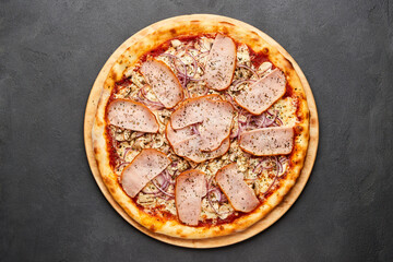 Delicious Italian Pizza with ham, onions and mozzarella cheese on dark background