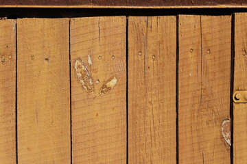 painted fence with planks texture old wood in warm colors. Vertical planks, painted brown. Wooden brown fence in warm colors.