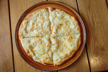 Fresh cheese pizza on a plate on the table, Italian traditional appetizer, high angle view.