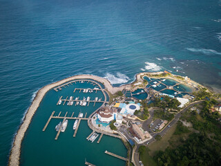 Aerial drone panoramic view of closed harbour with yachts, resort hotel, waves and blue water of...