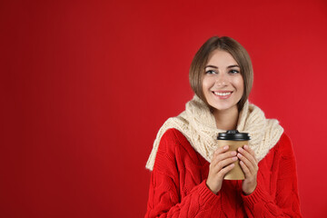 Happy beautiful woman with paper cup of mulled wine on red background. Space for text