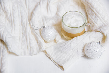 Autumn or winter cozy composition. Cup of coffee, warm knitted White sweater. Flat lay, top view