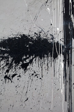 Splatter of black paint on a grey wall.