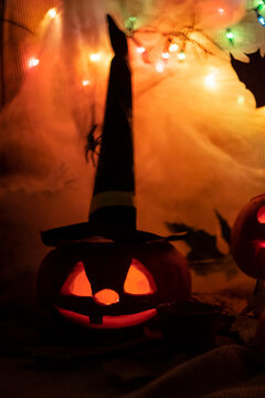 Halloween party decoration carved pumpkin in witch black hat spooky scary face with light in a dark