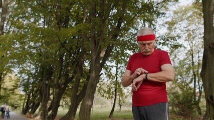 Senior runner man in park using smart watch, tracking distance, checking pulse after fitness workout