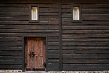 Obraz na płótnie Canvas Wall of dark wooden beams , small windows and vintage door.