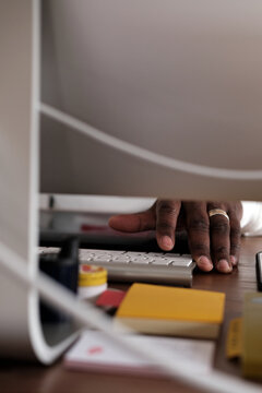 The hand of an African American male at work behind the computer.