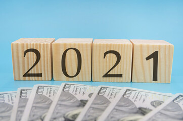 one hundred dollar bills on blue background / 2021 on wooden cubes / budget. Financial concept.