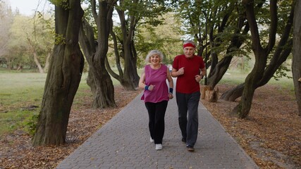 Obraz premium Active senior elderly couple doing cardio morning exercise workout. Man, woman running in city park.