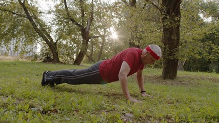 Active senior old man do push-ups physical exercises in park. Grandfather training fitness workout