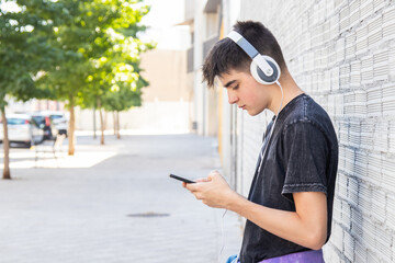 male teenager with mobile phone and headphones in the city