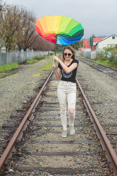 Teenage girl on the railroad tracks - windy day and her umbrella is flipped upward