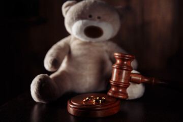 Divorce and alimony concept. Wooden gavel, rings and teddy bear as symbol of child. Family law