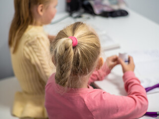 Fototapeta premium Adorable young girl in pink blouse with blond hair braided in a ponytail. Concept of discovery, pursuit of knowledge in children