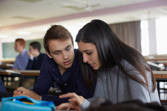 Attractive young couple of students sitting in a classroom