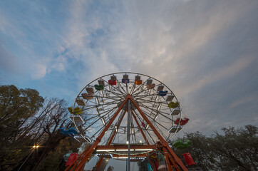 Ferris wheel bottom view in the early evening under blue sky at sunset