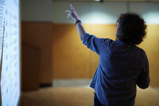Female speaker delivering a talk with screen and projector