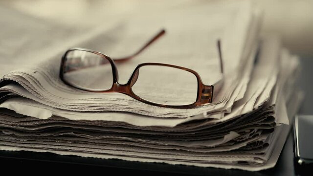 A stack of newspapers with glasses