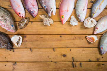 Top view of Caribbean Fresh fishes seafood on a rustic wooden table. The composition includes fish...