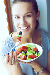 A beautiful girl eating healthy food, sitting near window