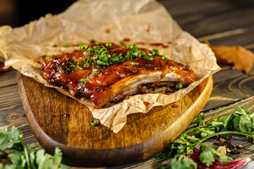 Pork ribs with green onions baked with sauce lie on a wooden Board