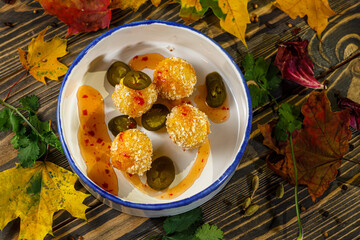 Potato croquettes with hot sauce and pepper are on a plate
