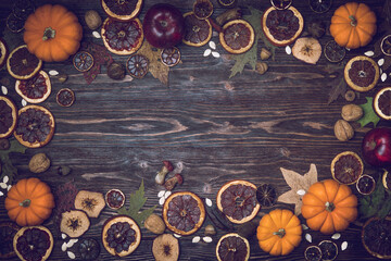 Autumn background with candied fruits, oranges, apples, nuts, seeds, mushrooms, acorns and pumpkin. Dry tree leaves. Natural wooden background with copy space. 
