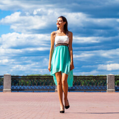 Happy beautiful brunette woman in a turquoise dress