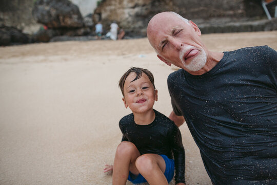 Happy grandpa and grandson playing together on the beach