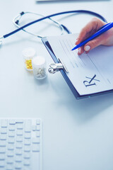 Woman's hands writing on sheet of paper in a clipboard with pen isolated on desk