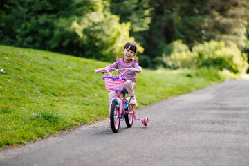 young girl ridding bicycle on summer garden morning