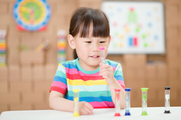 young girl plying hourglass learning the time for homeschooling