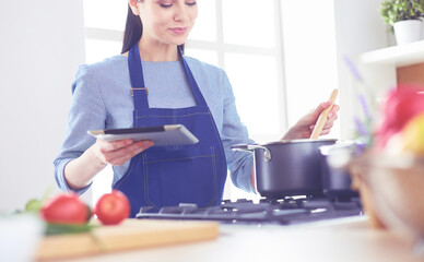 Young woman using a tablet computer to cook in her kitchen