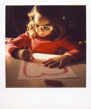 Polaroid Image Of A Cute Girl Coloring A Heart In Morning Sunlight While Wearing Sunglasses