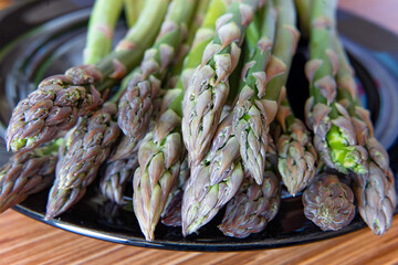 Fresh spring food - green asparagus on black dish, close up
