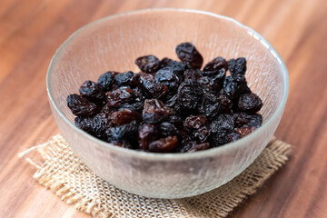 Raisins jumbo in glass bowl on wooden table - sweet healthy snack