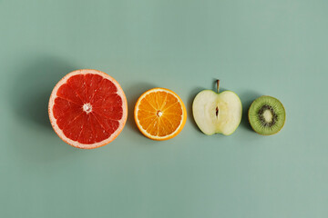 Pieces of fruit lies on a green paper background.