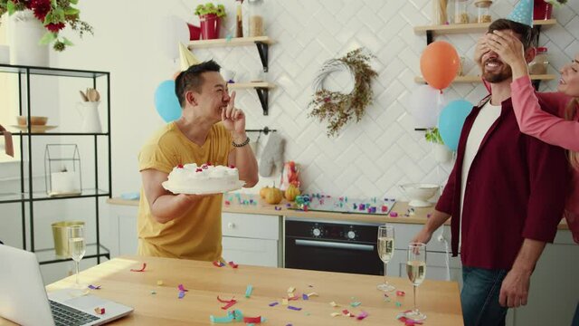 Multi-race happy colleagues making birthday gift surprise for their friend and smashing cake into his face. Entertainment. Real friendship goals. Fun concept.