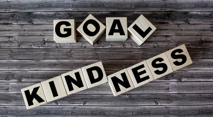 Kindness goal, text on wooden cubes and brown background.
