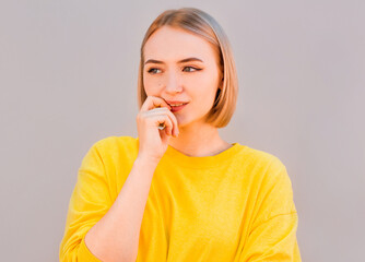 Young woman over isolated gray background looking stressed and nervous with hands on mouth biting...