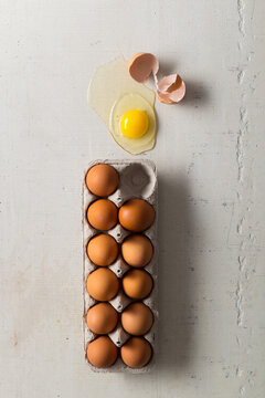 Brown Eggs in Carton with Broken Egg